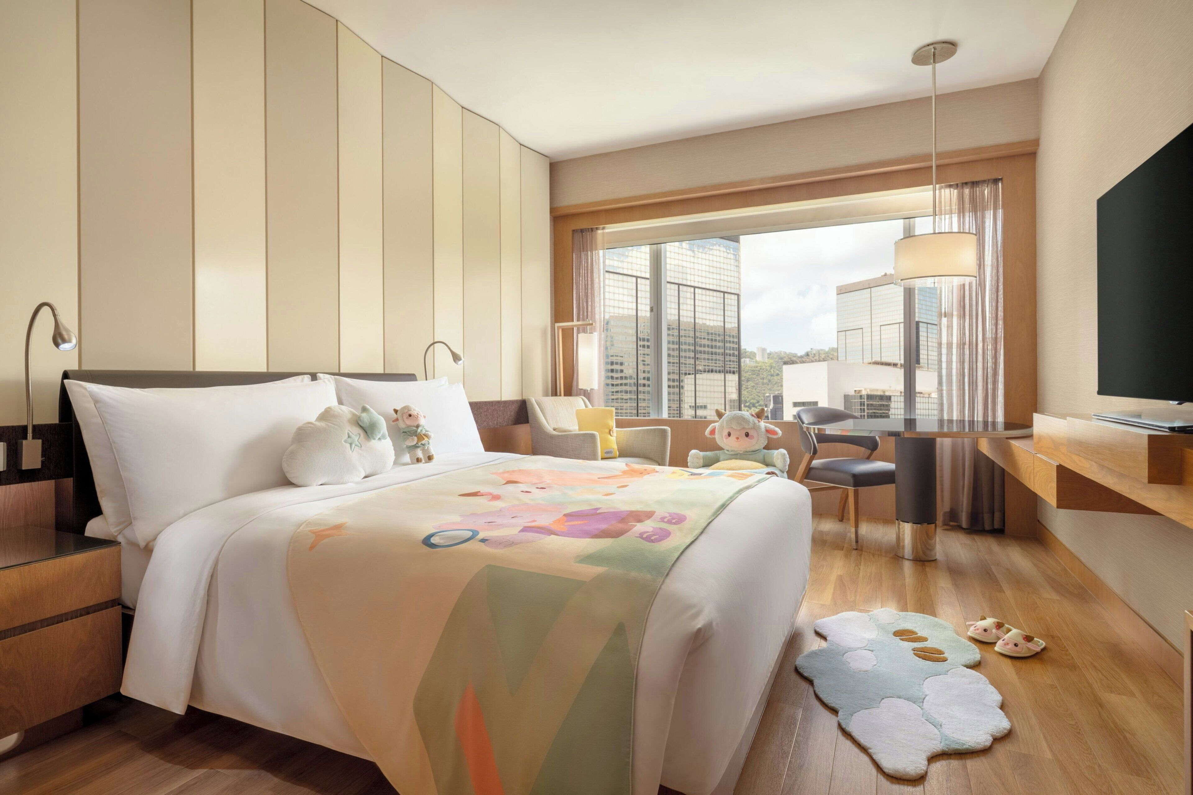 A hotel room with a bed, a desk, a chair, a TV, and a large window.