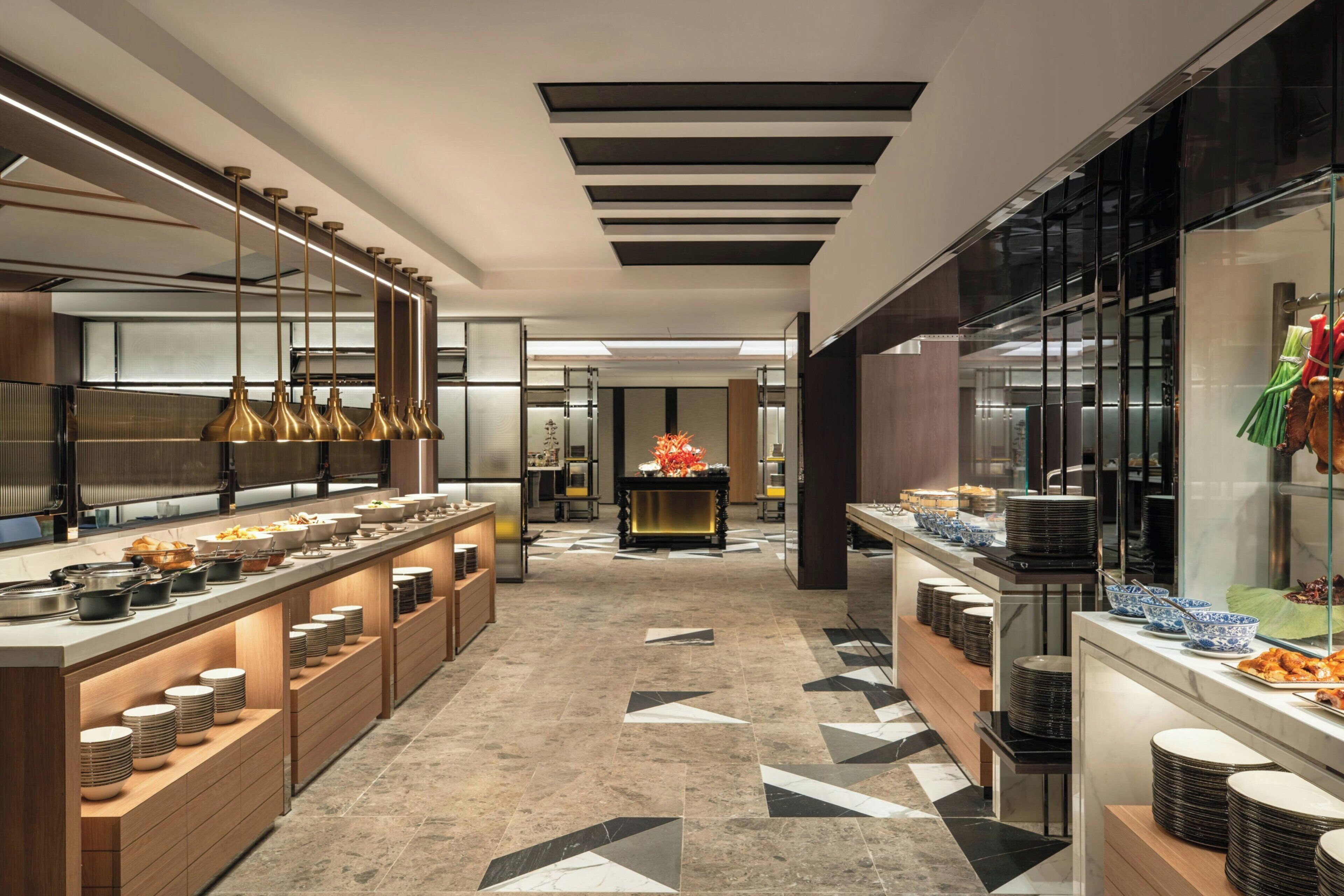 A modern kitchen with long countertops, multiple serving stations, and a central decorative piece.