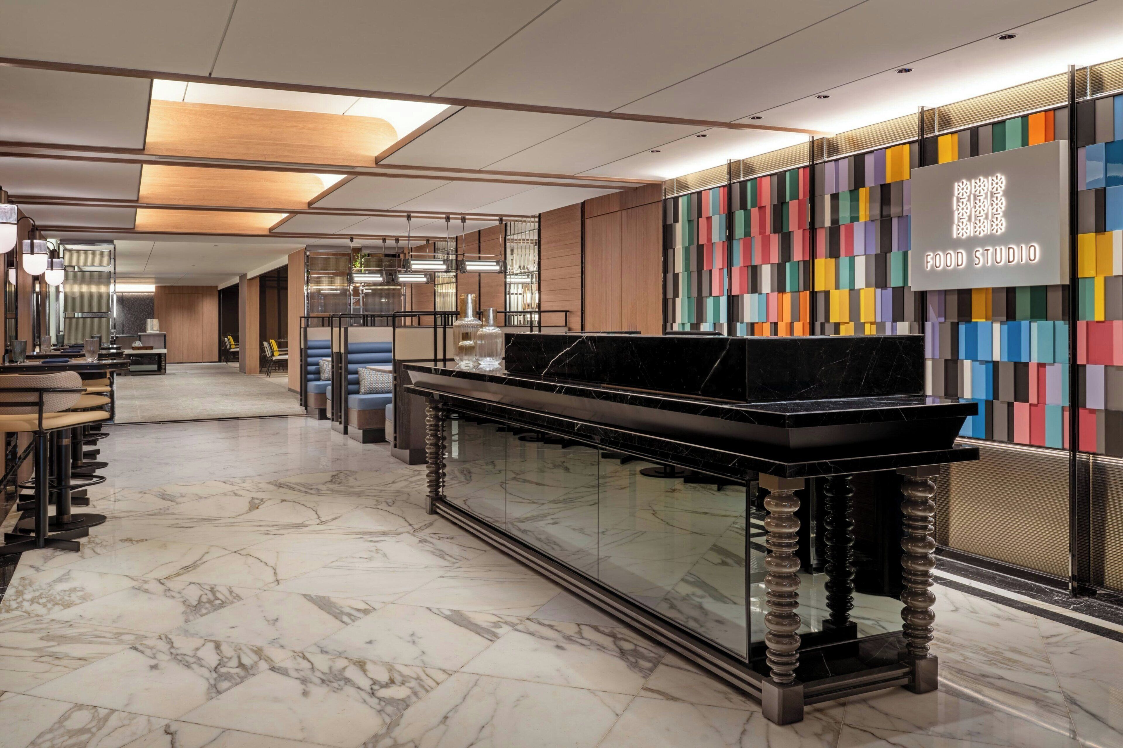 A modern interior with a marble floor, a black marble counter, and a colorful wall with a QR code.