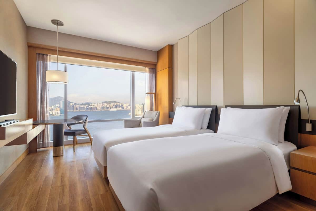 A hotel room with two beds, a desk, and a chair.