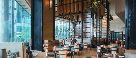 Un restaurante espacioso con techos altos, paneles de madera y amplias ventanas que ofrecen vistas al exterior.