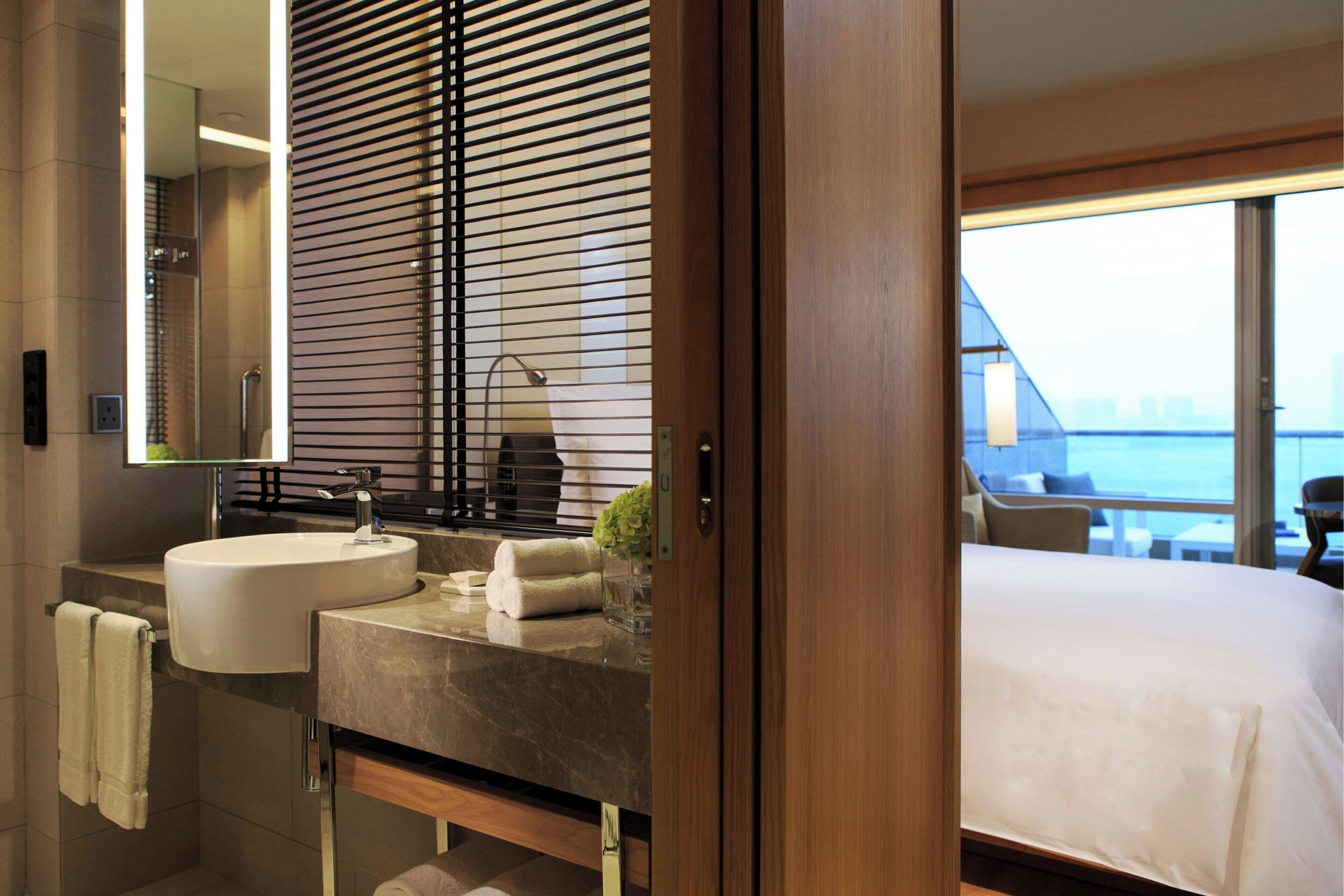 A modern bathroom with a large sink, mirror, and wooden blinds.