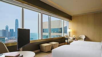 Una habitación de hotel con un ventanal grande, una cama, un escritorio y un televisor.
