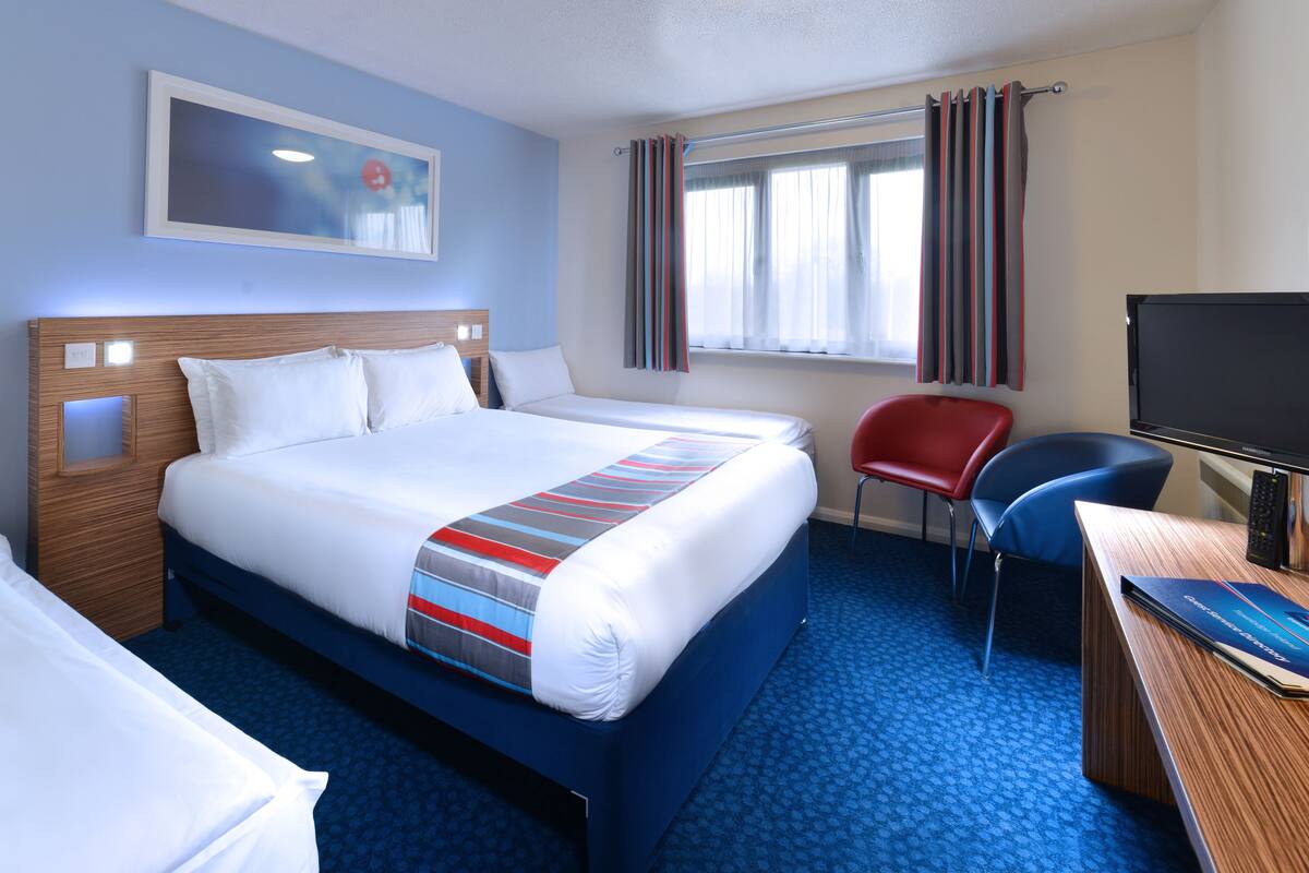 Una habitación de hotel con una cama grande, un escritorio con computadora, una silla y un televisor.