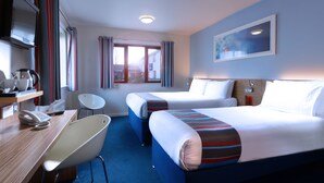 A hotel room with two beds, a desk with a telephone, a chair, and a window with curtains.