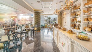 A spacious lobby with a polished marble floor, elegant furniture, and a variety of baked goods displayed on shelves. - Mövenpick Dubai Creek (Dubai)