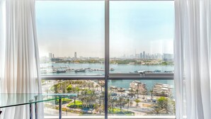 A view from a high-rise hotel room with a large window overlooking a marina and city skyline.