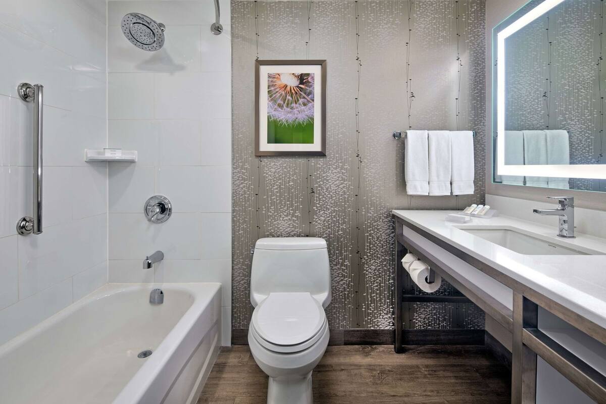 Un baño moderno con bañera, inodoro y tocador con espejo.