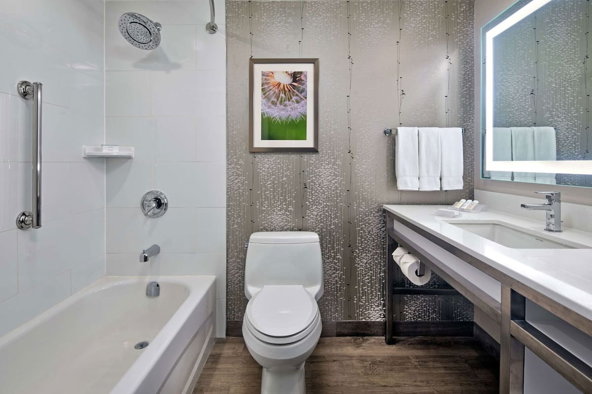 A modern bathroom with a bathtub, toilet, and vanity with a mirror.