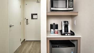 Una kitchenette compacta equipada con microondas, cafetera y lavavajillas.