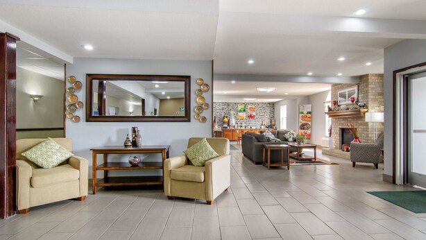 A spacious living room with a large mirror, two armchairs, a coffee table, and a fireplace. - Quality Inn Kearney - Liberty (Kearney)