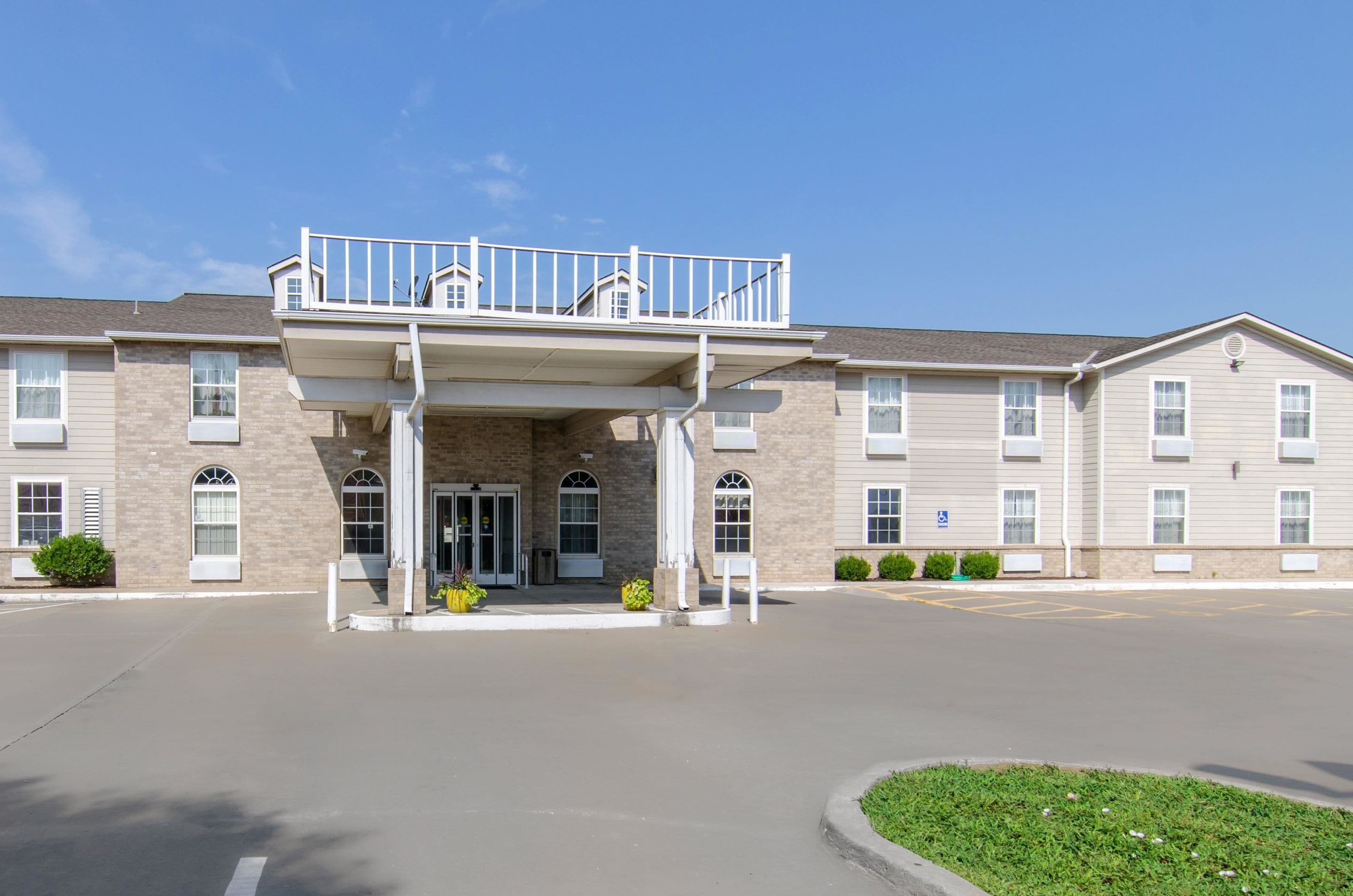 A two-story building with a covered entrance, multiple windows, and a parking lot.