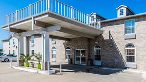 A building with a covered outdoor area, a brick facade, and a parking lot. - Quality Inn Kearney - Liberty (Kearney)