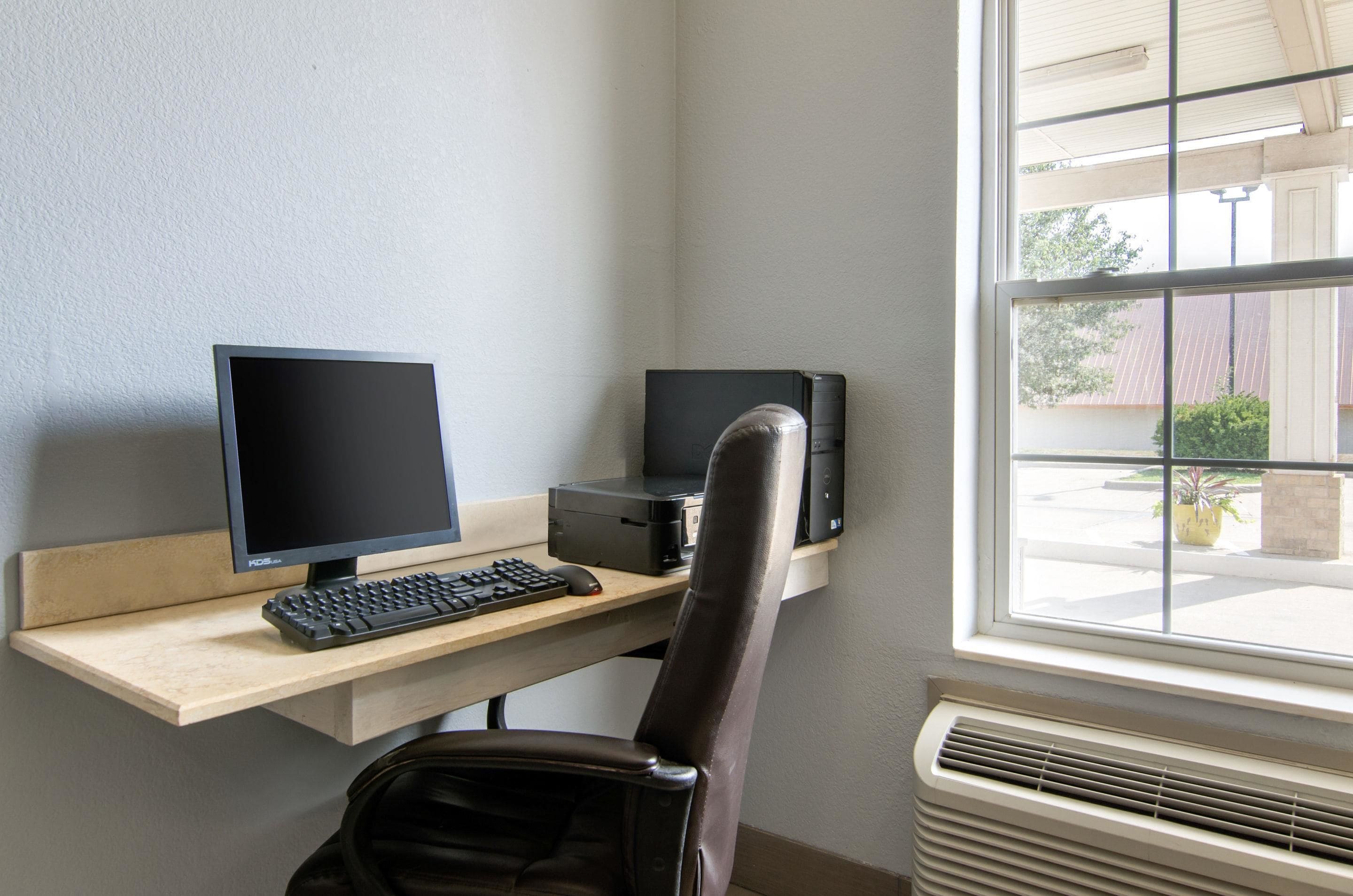A workspace with a desk, computer, keyboard, and chair.