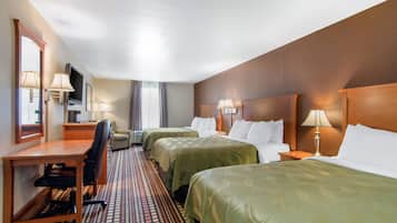 A hotel room with two beds, a desk, a chair, a TV, and a window with curtains.