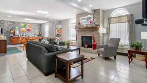 A spacious living area with a fireplace, a sofa, a dining area, and a kitchen in the background. - Quality Inn Kearney - Liberty (Kearney)