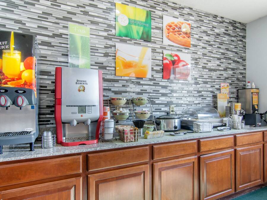 A hotel kitchen with a fruit juice dispenser, a coffee maker, and various kitchen appliances.