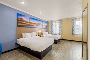 Een hotelkamer met twee bedden, een groot schilderij aan de muur en een raam met gordijnen met dessin.