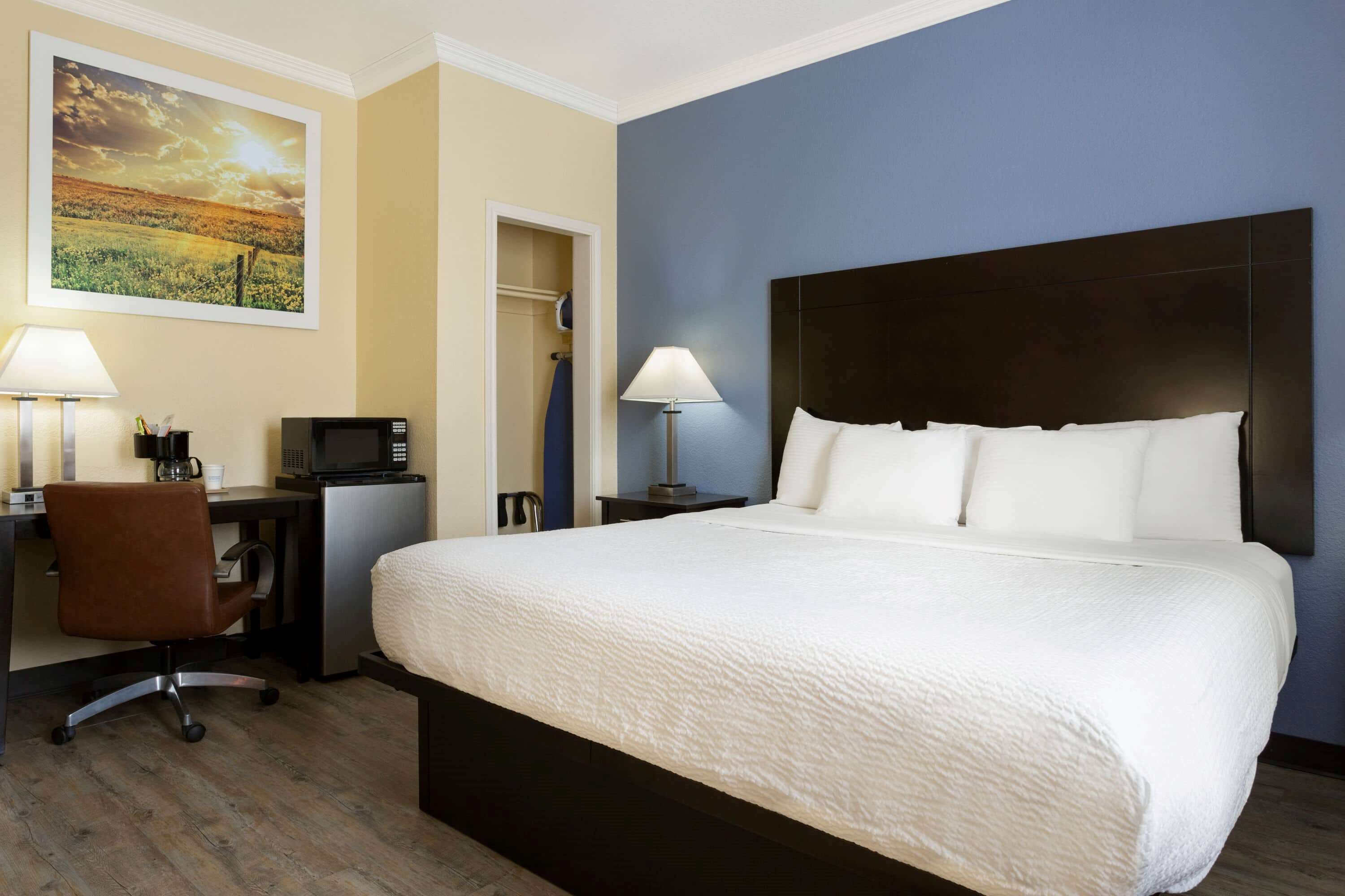 Une chambre d’hôtel avec un grand lit, un bureau avec un ordinateur, une chaise et une télévision.