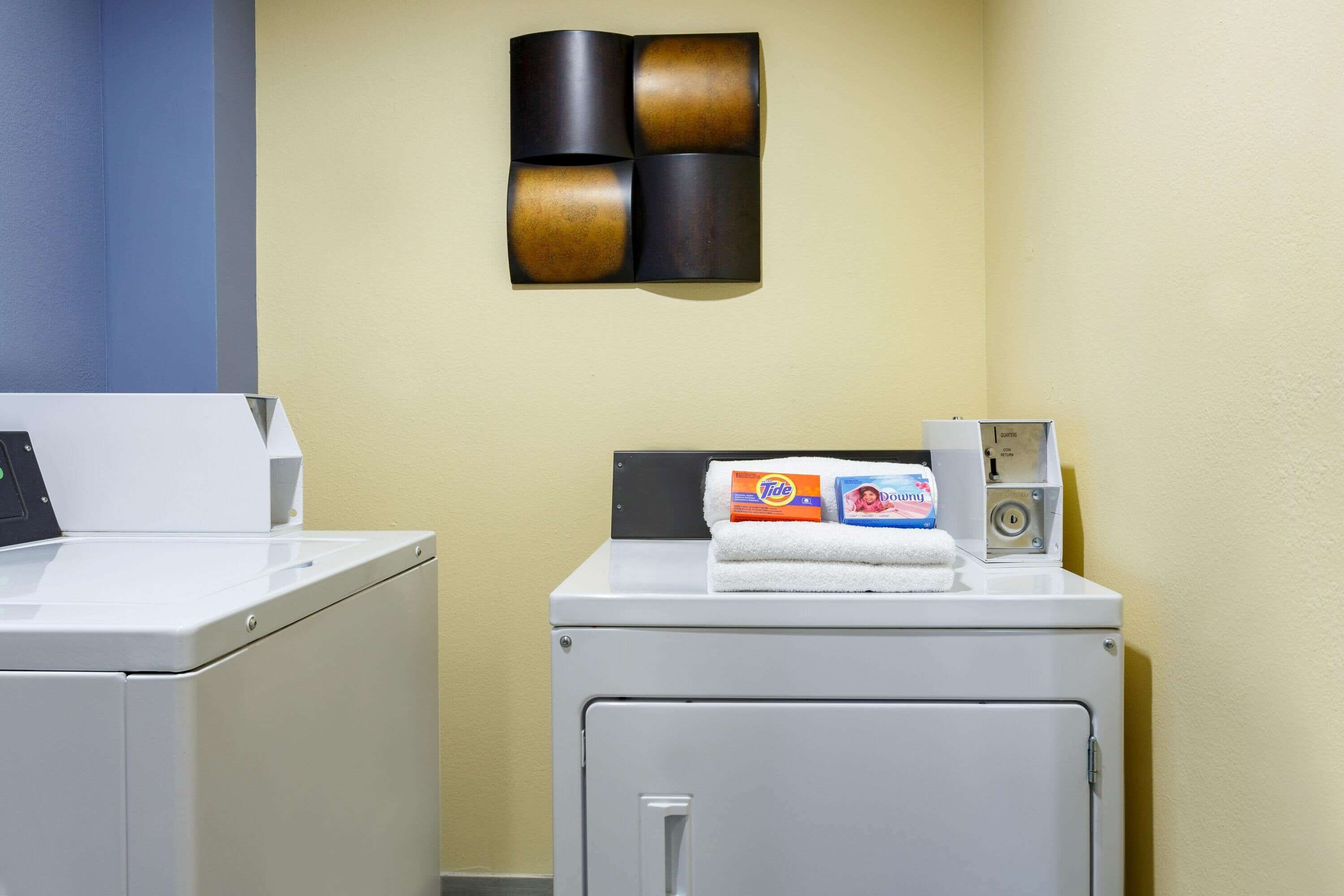 Un espace buanderie comprenant un lave-linge, un sèche-linge, une serviette et du détergent Tide.