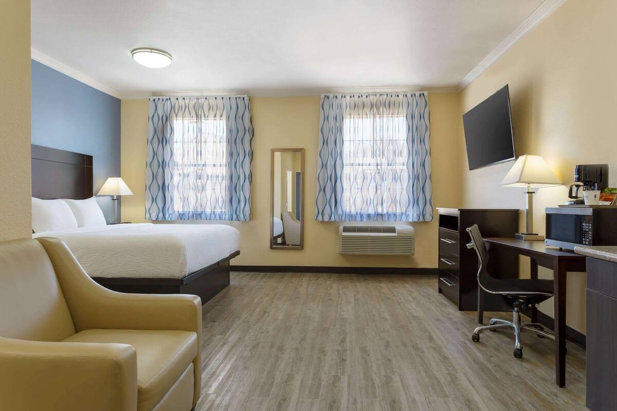 Ein Hotelzimmer mit einem Bett, einem Schreibtisch mit Stuhl, einem Fernseher und einer Schreibtischlampe.
