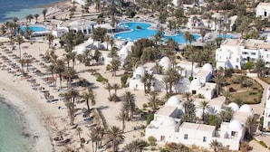 An aerial view of a resort with multiple swimming pools, palm trees, and beach areas. - El Mouradi Djerba Menzel (Aghir)
