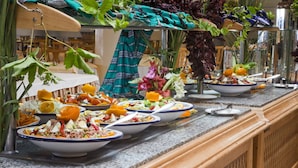 A buffet with various dishes and fresh vegetables displayed on a granite countertop. - El Mouradi Djerba Menzel (Aghir)