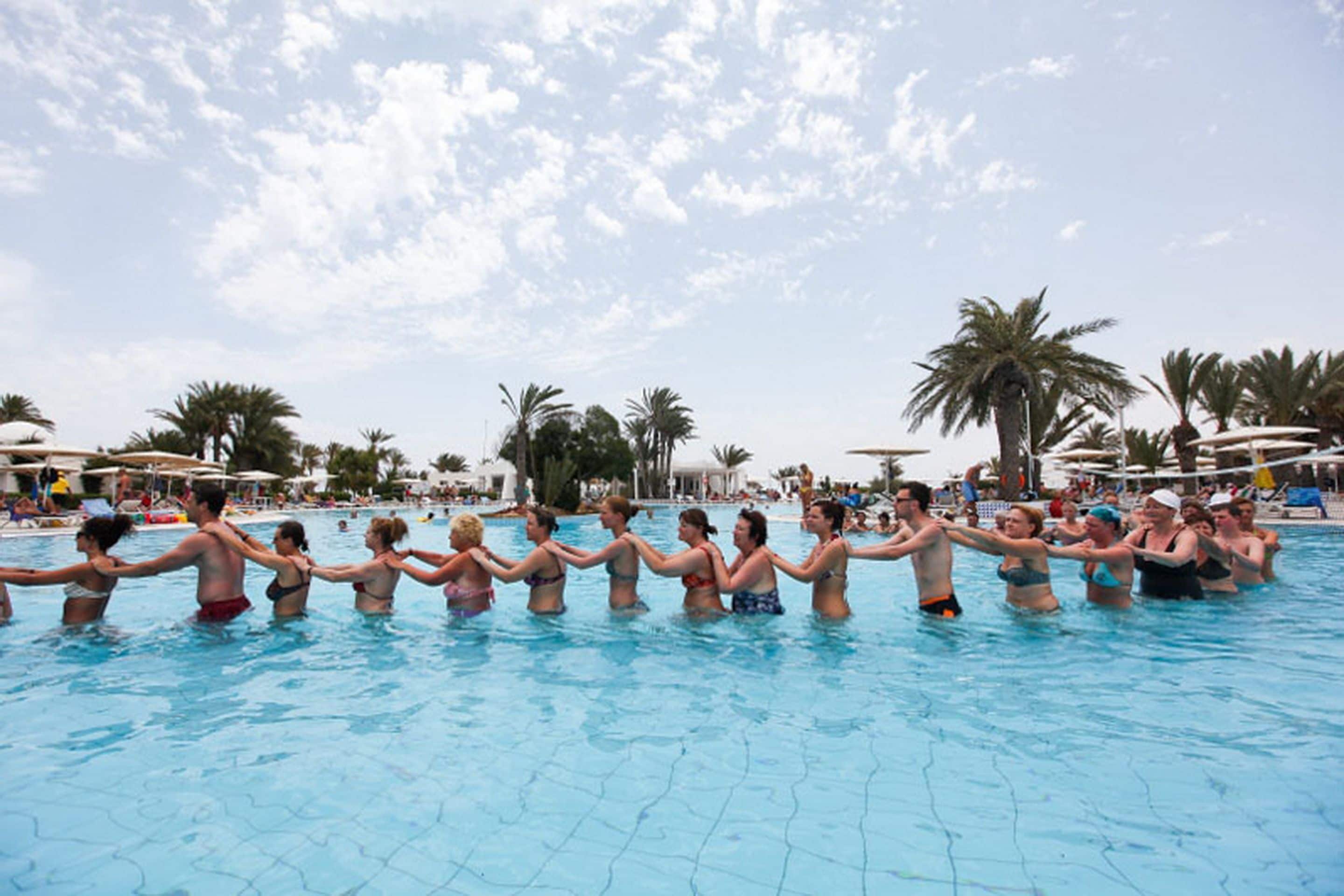 En swimmingpool med folk, der holder hånd i en række.