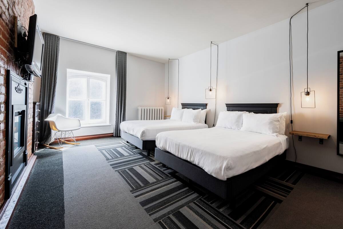 A hotel room with two beds, a seating area, and a large window.