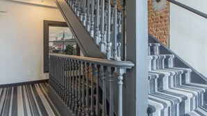 Un escalier recouvert d’une moquette à rayures, avec vue sur le paysage urbain par une fenêtre.