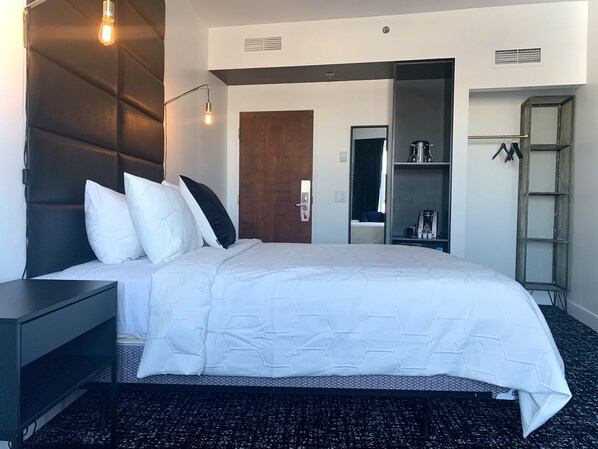 Una habitación de hotel con cama, mesita de noche, armario y espejo.