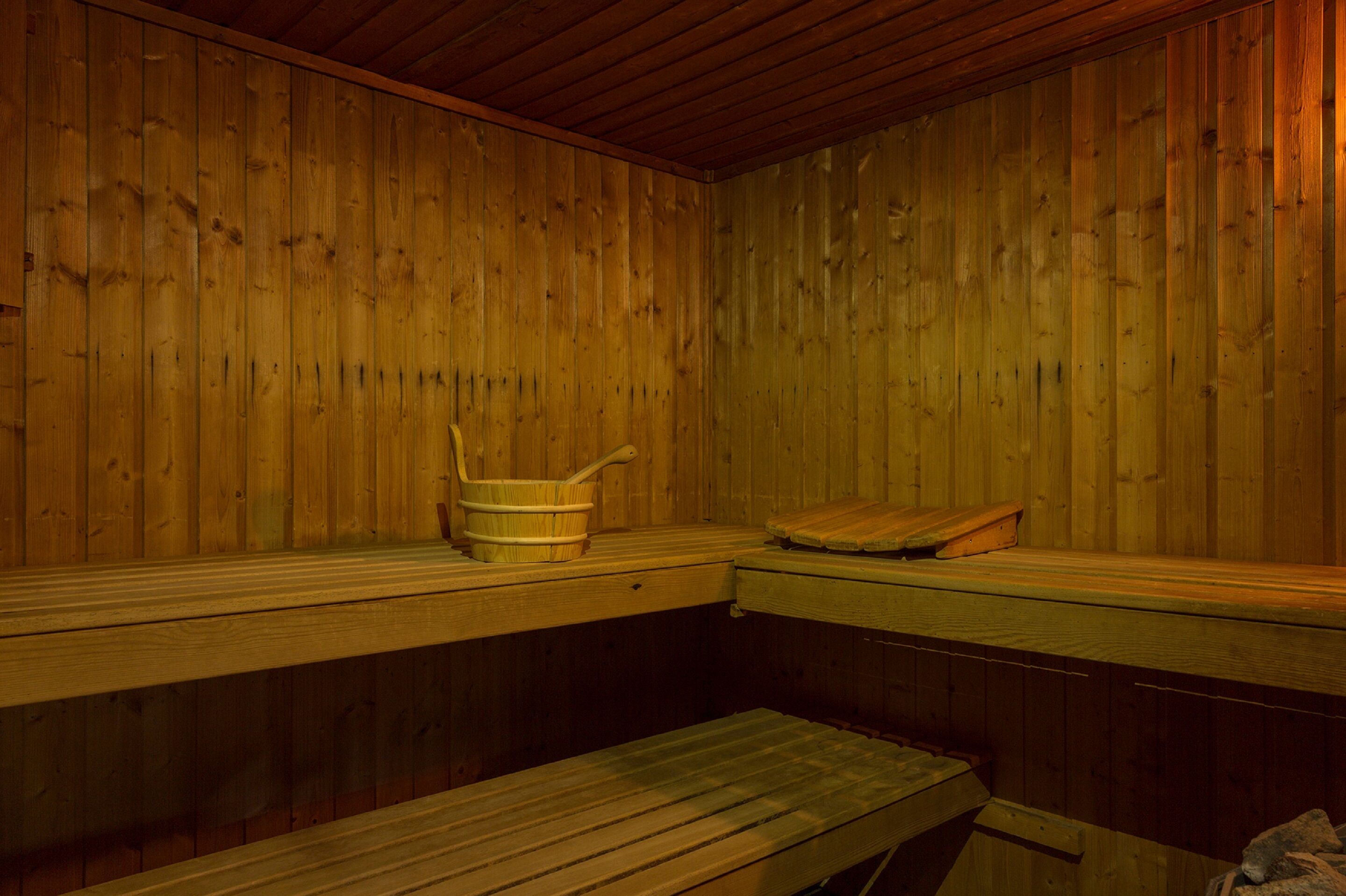 Una sauna con bancos de madera y un cubo de madera.