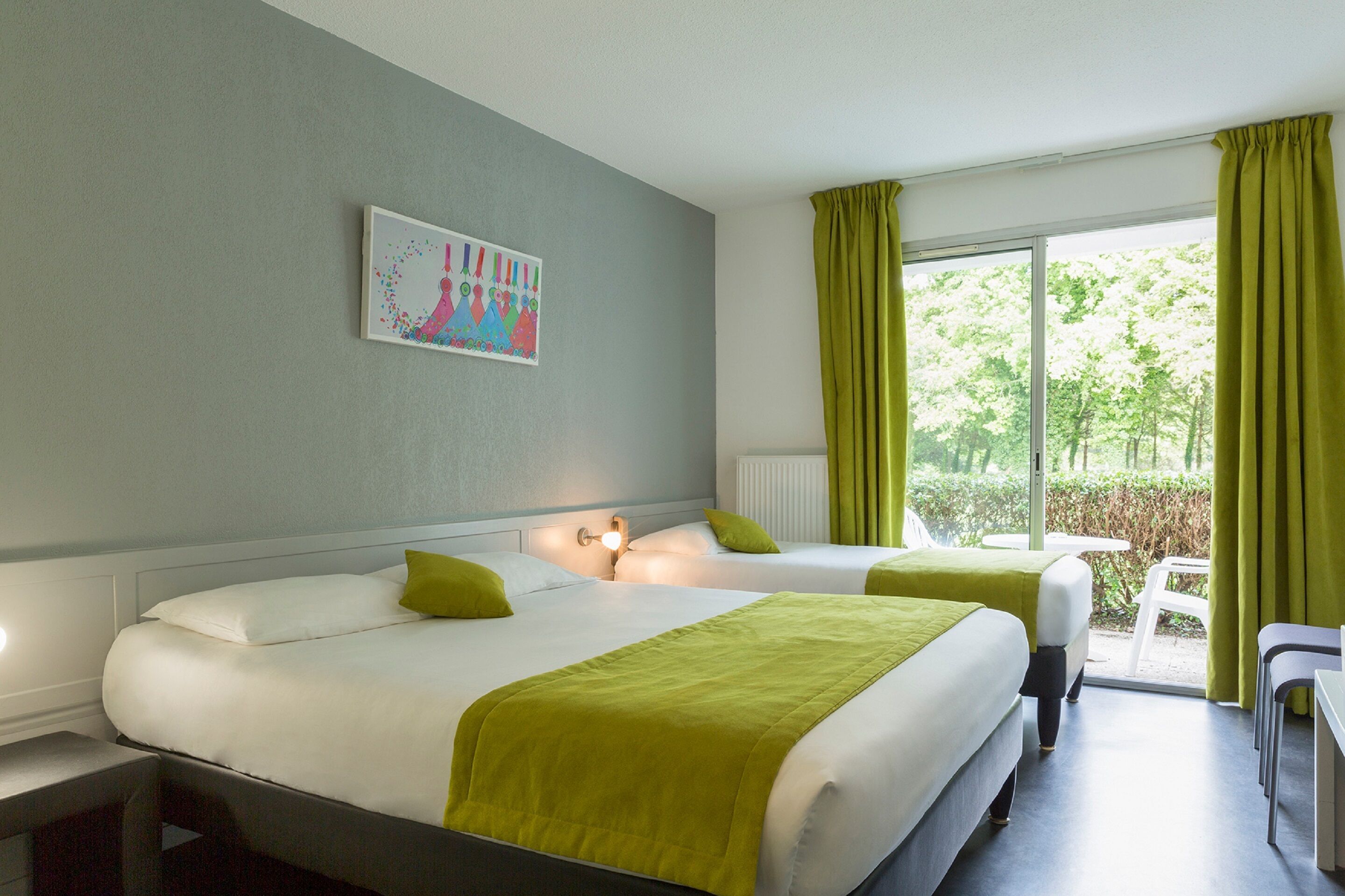 A hotel room with two beds, a window with curtains, a small table, and a painting on the wall.