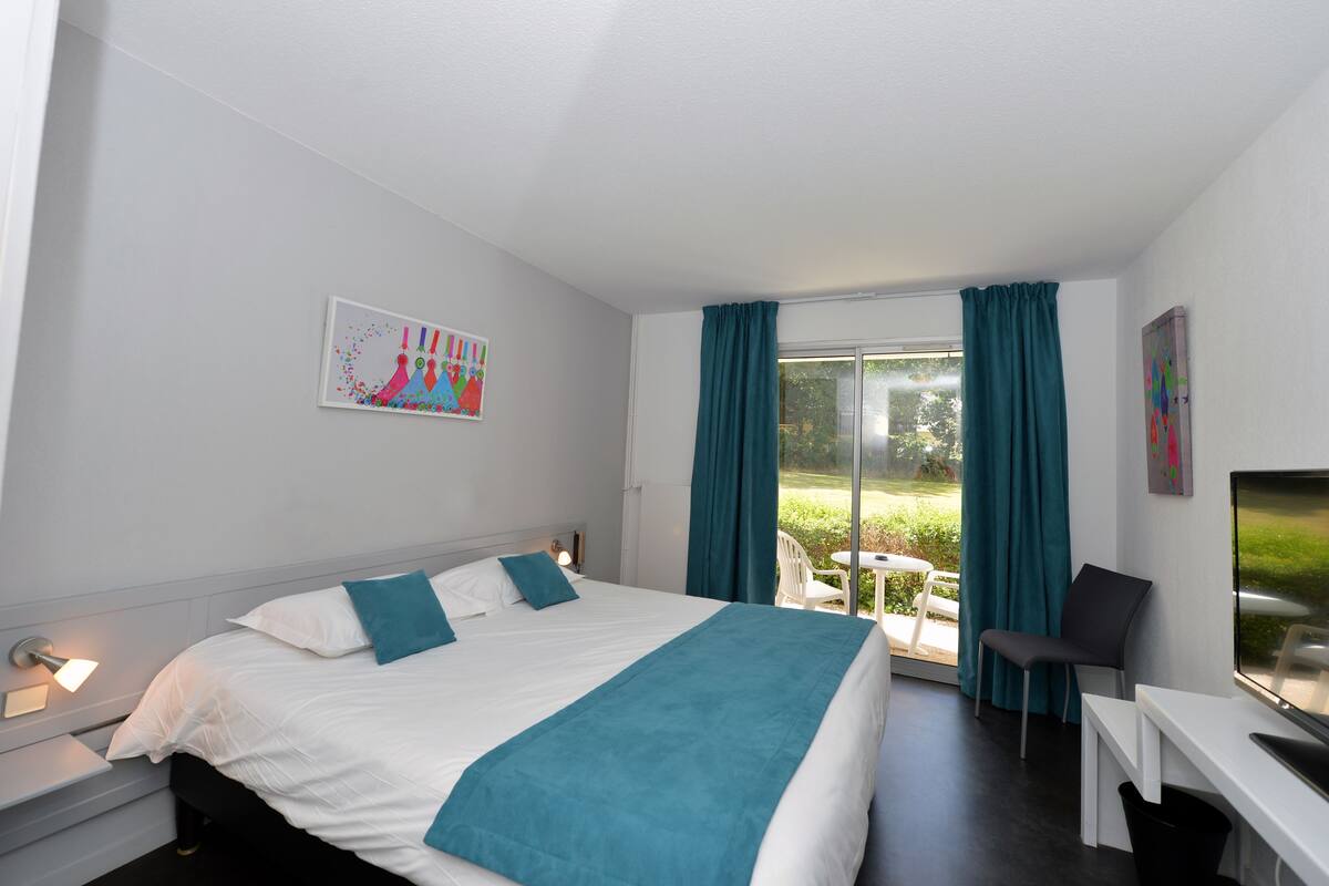 Una habitación de hotel con cama, escritorio, silla y televisión.