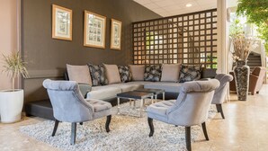 Una sala moderna con un sofá modular, dos sillones, una mesa de centro y un separador decorativo.