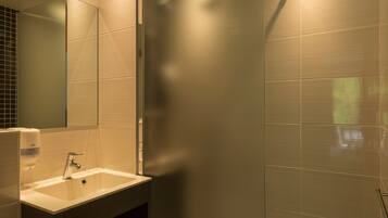 A bathroom with a sink, mirror, and tiled walls.