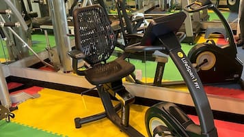 Un gimnasio con equipo de ejercicios, incluyendo una cinta de correr y máquinas de pesas.