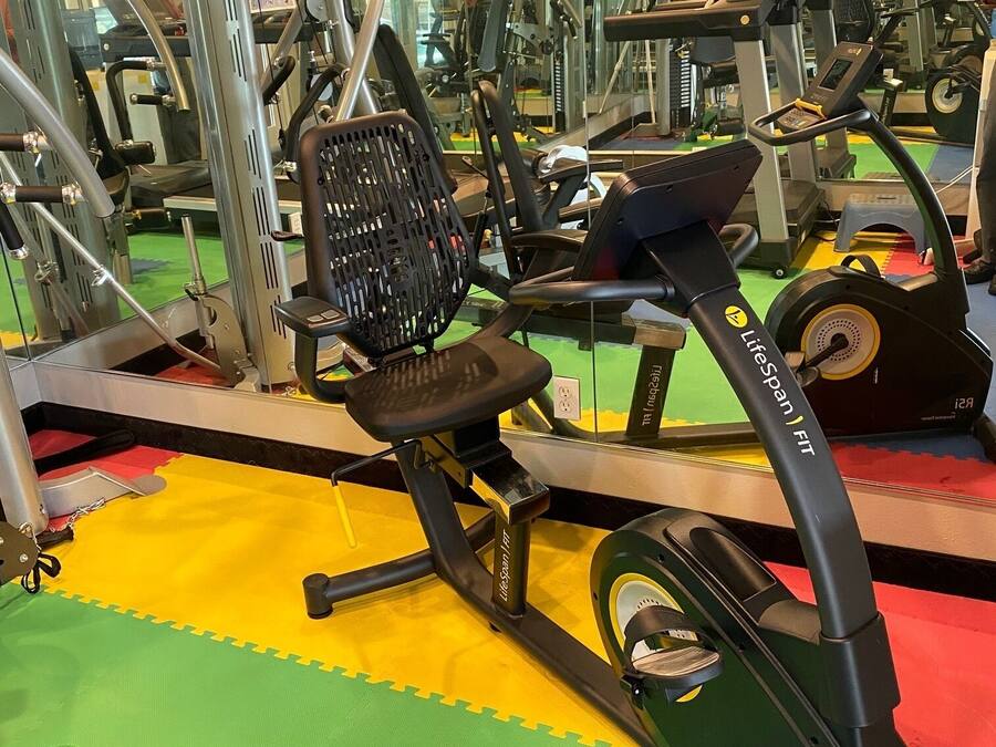 Un gimnasio con equipo de ejercicios, incluyendo una cinta de correr y máquinas de pesas.