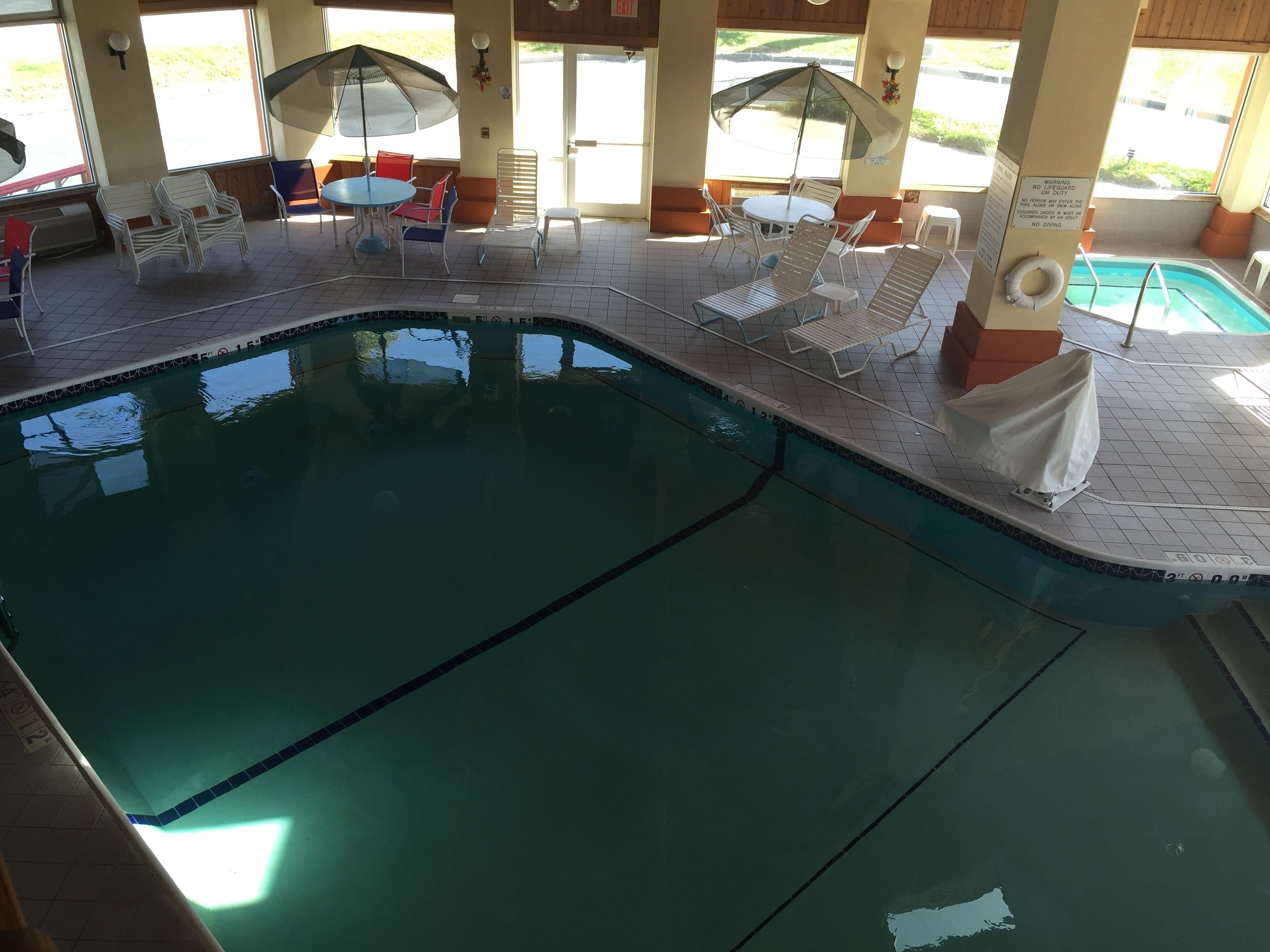 Una piscina interior amb gandules i ombrelles.