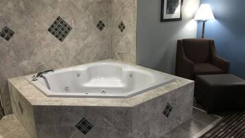 Un baño con una bañera independiente, una silla y una lámpara.