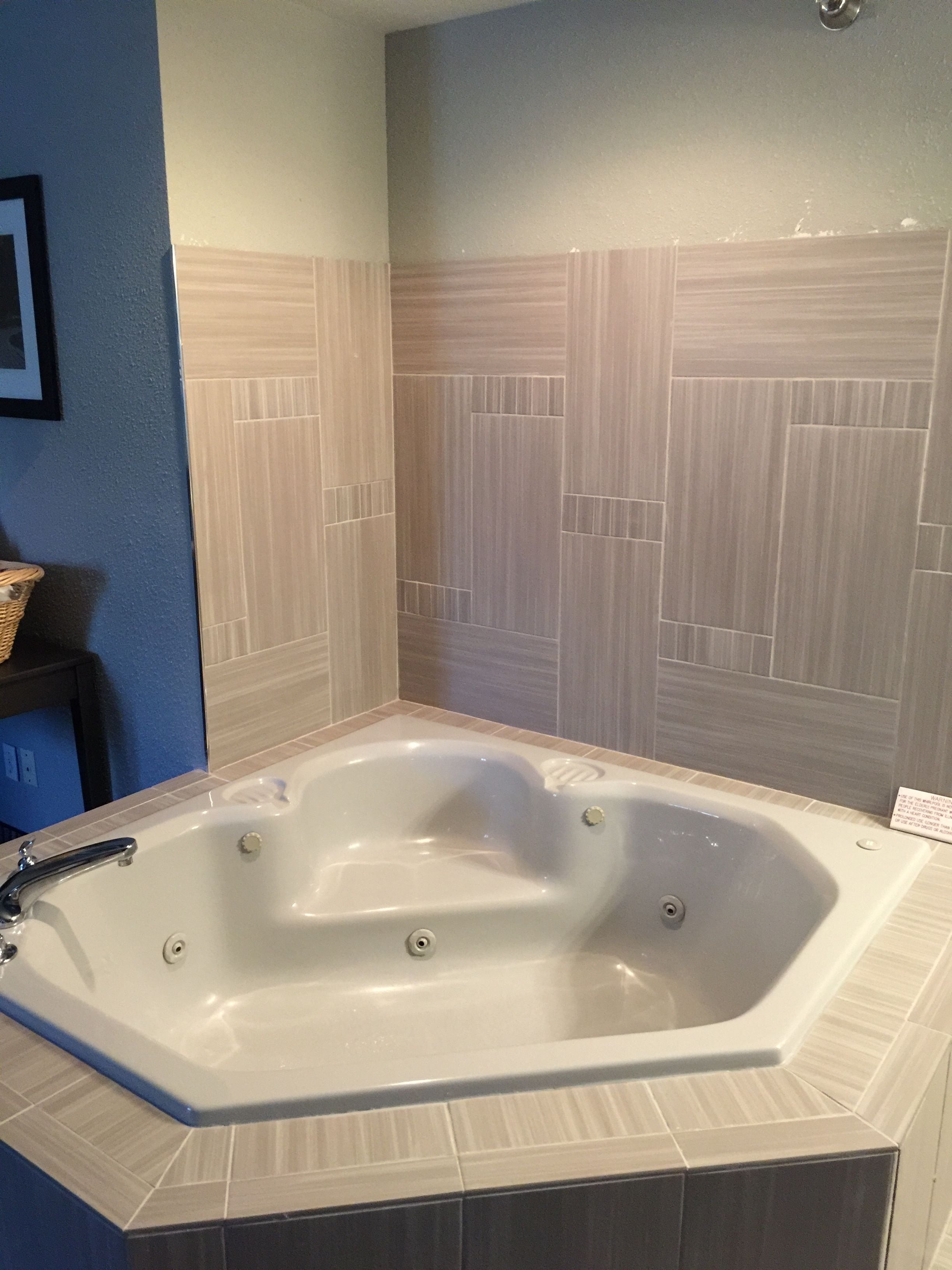 A bathroom with a freestanding bathtub, tiled walls, and a small stool.