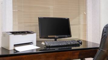 Ein Computertisch mit einem Samsung-Monitor, einer Tastatur und einem Drucker.