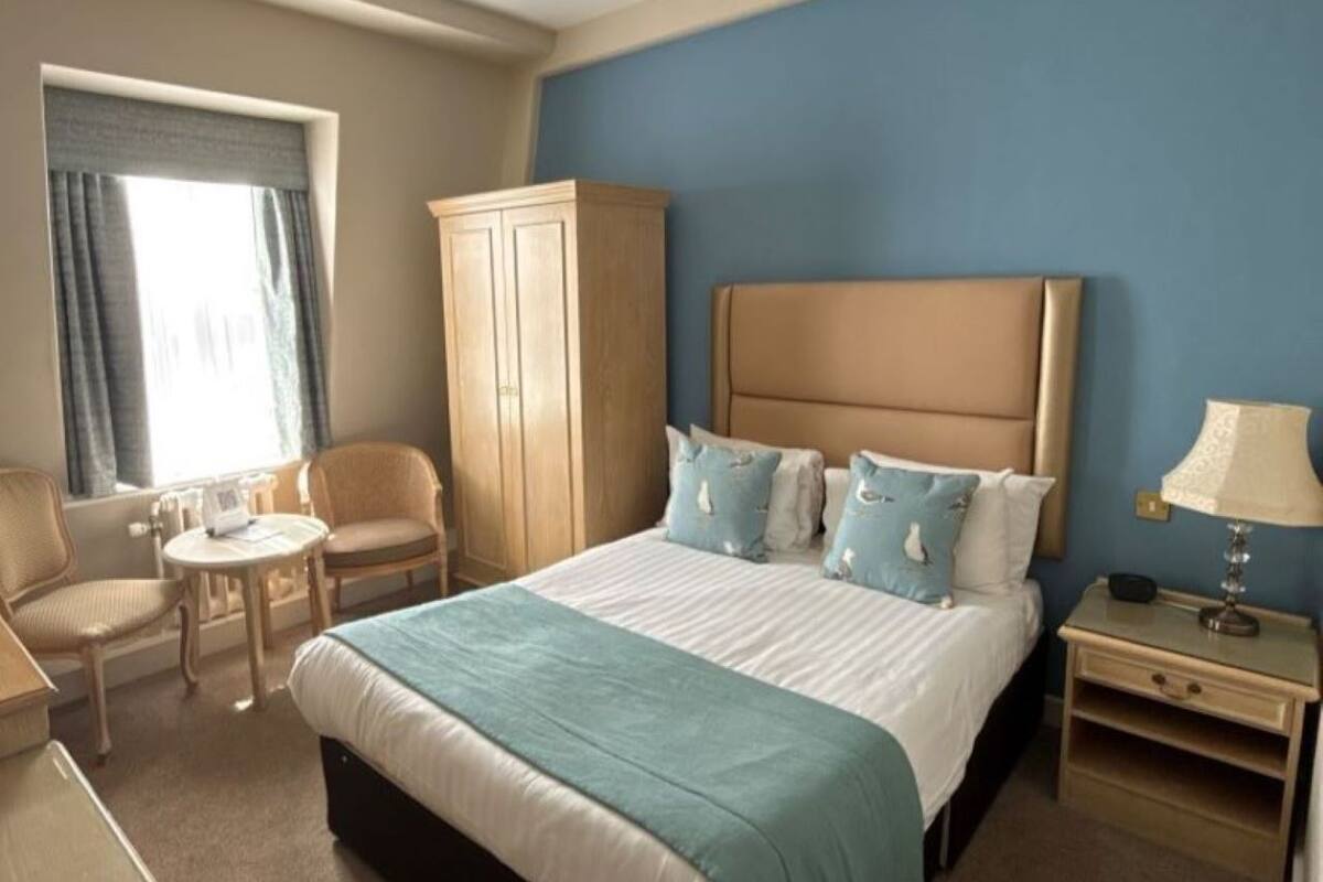 Ein Hotelzimmer mit Bett, Stuhl, Tisch, Kleiderschrank und Nachttisch.