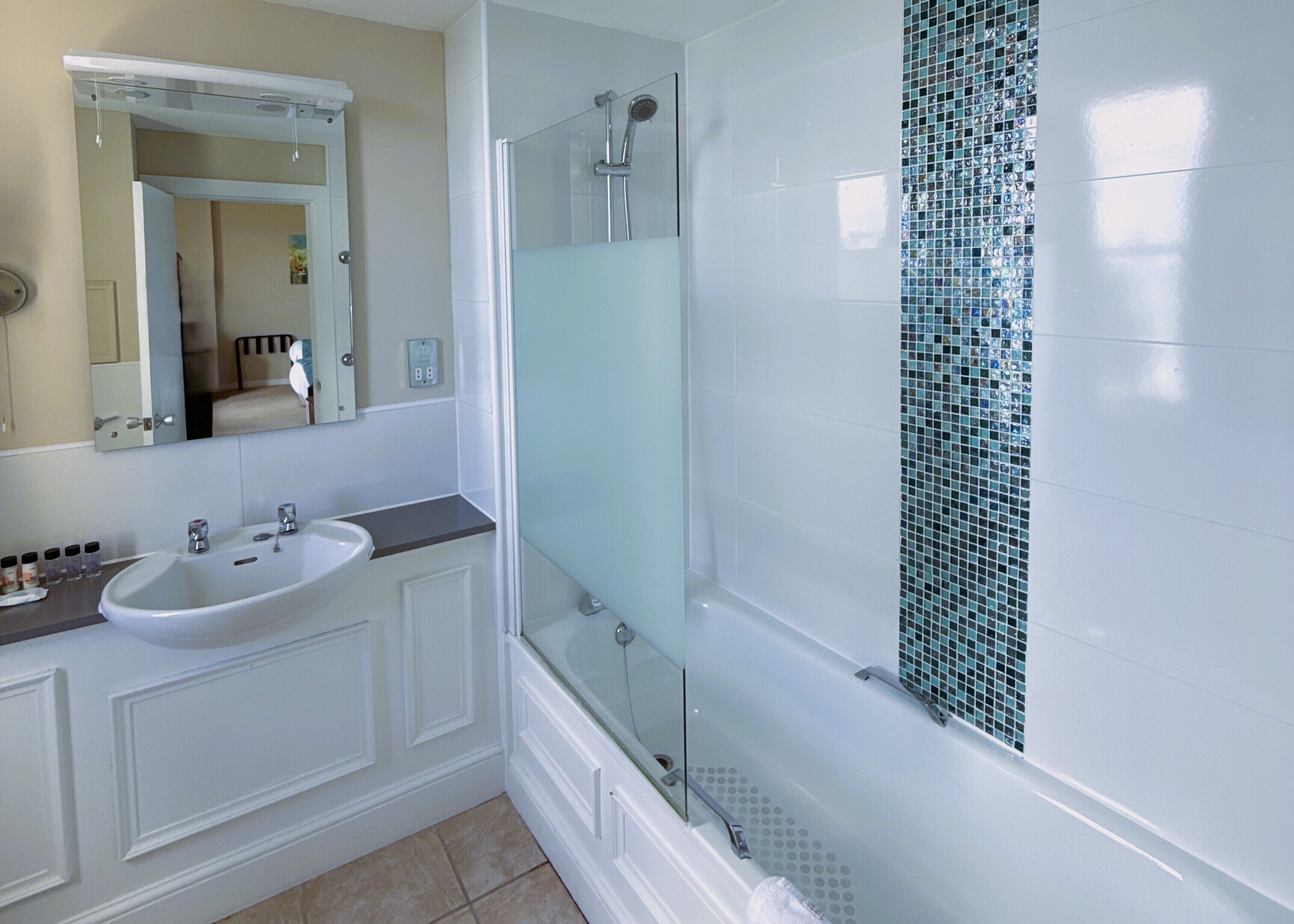 A modern bathroom with a white sink, a glass shower enclosure, and a tiled shower wall.