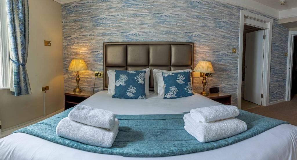 Ein Hotelzimmer mit einem großen Bett, zwei Nachttischlampen und einer strukturierten Wand.