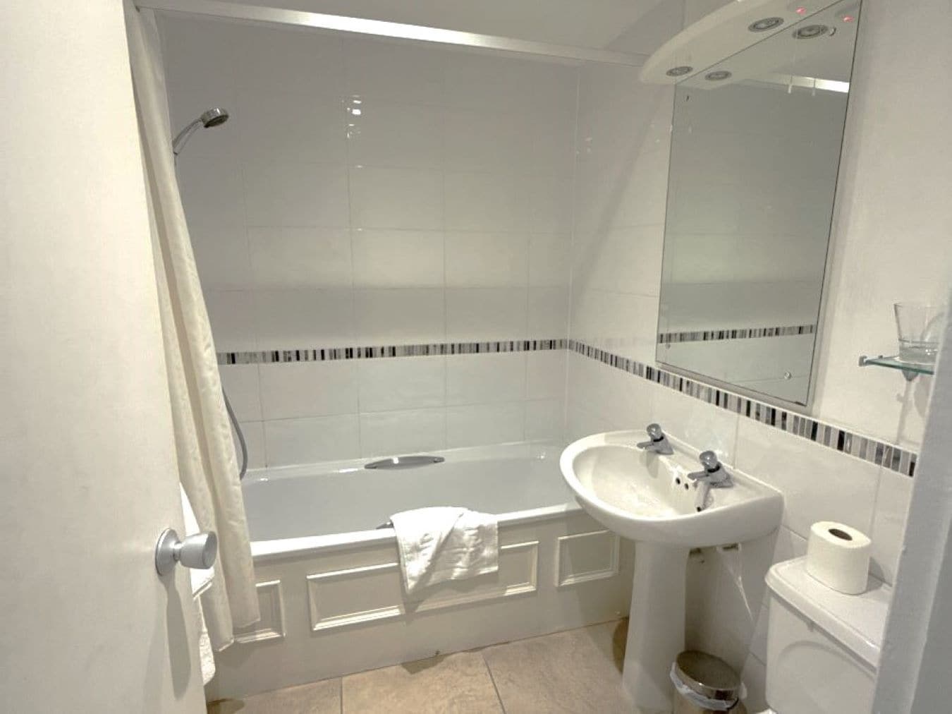 A bathroom with a bathtub, a sink, a toilet, and a mirror.