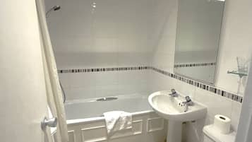 A bathroom with a bathtub, a sink, a toilet, and a mirror.
