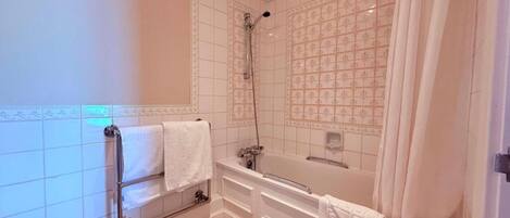 A bathroom with a bathtub, shower, and a towel rack.