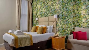 A hotel room with a bed, bedside table, and a sofa.
