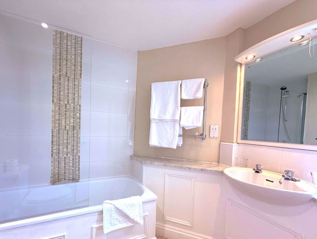 A modern bathroom with a large bathtub, a sink, and a mirror.